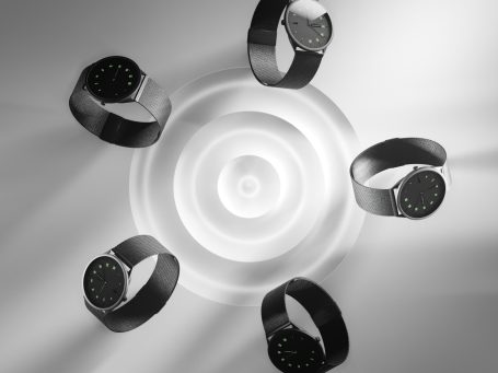 Fünf elegante Uhren in Schwarz mit minimalistischen Zifferblättern auf hellem Hintergrund. 3D Visualisiert.