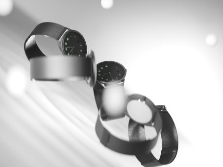 Mehrere moderne Uhren mit schwarzem Armband und grünem Ziffernblatt auf unscharfem Hintergrund. 3D Visualisiert.